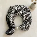 Detail shot of black and white zebra stripe silk scarf featuring a chic pearl magnetic clip. - Zebra Print