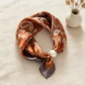 Detailed view of retro paisley print silk satin neckerchief with an elegant pearl magnetic clasp. - Vintage Paisley