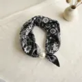 Vista detallada de un pañuelo de seda en blanco y negro con una elegante hebilla de perla. - Círculos negro - CXK006