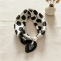 Dettaglio in primo piano di un elegante foulard in seta a pois neri e bianchi con perla. - Riga Pois