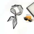 Detailed view of black and white paisley skinny twilly scarf with elegant black bead necklace. - Paisley White