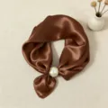 Primo piano dettagliato di un foulard da collo in raso marrone di lusso con fibbia di perle. - Marrone