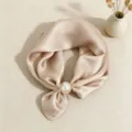 Vista dettagliata di un elegante foulard in raso beige con chic fibbia ad anello di perla. - Champagne Tinta Unita