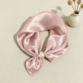 Dettaglio ravvicinato della elegante sciarpa in satin rosa con grande fibbia a perla. - Rosa
