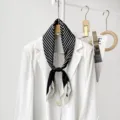 Close-up of elegant black and white striped silk scarf styled on white blazer hanger. - CXK010 - Black Meander Pattern