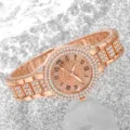 Nahaufnahme einer roségoldenen Damenuhr, die komplett mit glitzernden Strasssteinen besetzt ist. - Roségold
