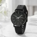 Nahaufnahme einer minimalistischen schwarzen Silikonuhr mit weißen Zahlen und Herzzeiger - Schwarz