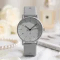 Nahaufnahme einer minimalistischen grauen Silikonuhr mit Zifferblatt und Blumenhintergrund. - Grau