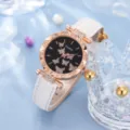 Nahaufnahme der eleganten Damenuhr mit Glitzer-Schmetterlingszifferblatt und Lederarmband - Weiß