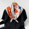 Détail en gros plan d'un foulard carré élégant avec de superbes motifs floraux colorés. - Orange Bleu