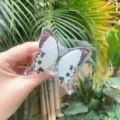 Close-up of white butterfly acrylic phone grip being held against a leaf background - Expanding Stand / White Butterfly