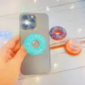 Detailansicht eines niedlichen blauen Donut-Handyhalters an einem grauen Smartphone. - Erweiterbarer Ständer / Blauer Donut