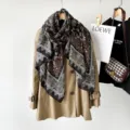 Detailed view of women's autumn paisley print cotton linen scarf draped elegantly on a trench coat. - Black