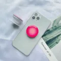 Detail eines rosa Farbverlauf klappbaren Handy-Grip-Ständers an einem Smartphone - Halterung mit Weißer Basis / Rosa
