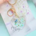 Detailed view of heart resin keychain with real blue flowers and elegant gold foil flakes - White & Blue Tiny Flowers