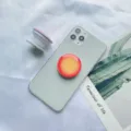 Makroansicht des rot-gelben Verlaufs-Handy-Griffs aus Harz auf einem Smartphone. - Halterung mit Weißer Basis / Orange