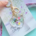 Close-up of a heart-shaped resin keychain with real dried flowers and gold foil. - Four-Color Tiny Flowers