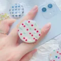 Detail van de iriserende schelppatroon telefoonhouder met kersenprint op een smartphone - 1.1
