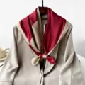 Close-up detail of the elegant color-block silk scarf draped on a stylish blazer. - Red