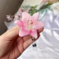 Detalle de cerca de un porta acreditación retráctil de lirio rosa sobre tela blanca. - Rosa Claro