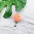 Detailansicht runder ausziehbarer Ausweishalter mit orangefarbenen Herz-Pailletten - Orange Herz