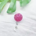 Nahaufnahme eines runden pinkfarbenen Glitzer-Ausweishalters auf weißem Leinenhintergrund - Magenta Konfetti