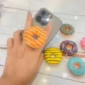 Detaillierte Makroansicht eines realistischen 3D-Donut-Handyhalters an einem Smartphone - Erweiterbarer Ständer / Orange Donut