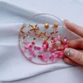 Detailed macro view of a handmade circular resin coaster with gold foil and starfish charms. - Pink Ocean Round Coaster