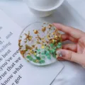 Close-up of a handmade resin coaster with gold foil, green stones, and golden charms - Green Ocean Round Coaster