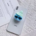 Detailopname van pluchen telefoonhouder met miniatuur muts en hartjes zonnebril - Pompon Muts Houder / Hemelsblauw