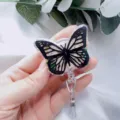 Hand holding butterfly retractable badge holder with real flowers and gold foil - Black Butterfly White Flower