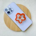 Close-up detail of a vibrant orange acrylic flower phone griptok on a purple smartphone - Support / Red Small Flower