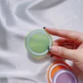 Detalle de una base de anillo magnético MagSafe verde sobre satén blanco - Disco Magnético / Verde claro