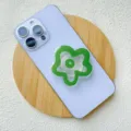 Close-up of green flower-shaped acrylic phone grip on light purple smartphone back - Support / Green Flower