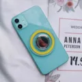 Primer plano de un teléfono verde menta con soporte de anillo magnético MagSafe amarillo - Hebilla de Anillo Magnética / Amarillo