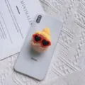 Detailopname van een schattige pluchen telefoonhouder met gele hoed en hartjesbril - Pompon Muts Houder / Khaki