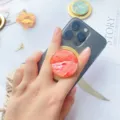 Makrodetail eines magnetischen Handyhalters aus natürlicher Muschel an einem Smartphone - Magnetischer Ständer / Rote Muschel Goldrand