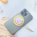 Detailansicht des rosa Perlmutt-Magnet-Handyhalters auf einem grauen Smartphone - Magnetischer Ständer / Lila Muschel Goldrand
