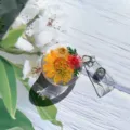 Κοντινό πλάνο αναδιπλούμενης θήκης σήματος με αληθινά αποξηραμένα λουλούδια σε ρητίνη. - Στυλ 3 Πραγματικό Λουλούδι