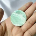 Vue rapprochée d'un disque de nacre naturelle vert clair iridescent tenu dans la main - Vert Rond