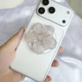Nahaufnahme des schimmernden Handy-Griffs aus Kunstharz in Blumenform auf einem Smartphone - Magnetischer Ständer / Hellkaffee