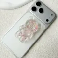 Detail showing a 3D transparent bear phone grip filled with pink petals on a white phone - Adhesive / Pink