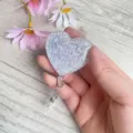 Nahaufnahme einer herzförmigen silbernen Glitzer-Ausweishülle, in der Hand gehalten - Silber