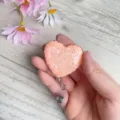 Nahaufnahme des herzförmigen rosa Glitzer-Ausweis-Jojos mit einziehbarem Clip in der Hand - Kirschblütenrosa