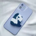 Close-up view of a cute panda acrylic phone grip holder attached to a purple smartphone - Expanding Stand / Left Hand Panda