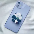 Close-up of a cute panda acrylic phone grip stand attached to a purple smartphone. - Expanding Stand / Sitting Leaf Panda