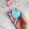 Nahaufnahme eines herzförmigen Glitzer-Ausweishalters mit Clip in der Hand - Himmelblau