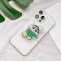 Nahaufnahme der Crayon Shin-chan Handyhalterung aus Acryl an einem weißen Smartphone - Erweiterbarer Ständer / Mi Charakter Stil