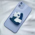 Detailed macro view of a cute cartoon panda acrylic phone socket grip on a purple device - Expanding Stand / Right Hand Panda