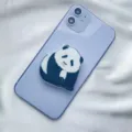 Detailed close-up showing a cute panda acrylic phone grip attached to a purple smartphone - Expanding Stand / Sitting Tilted Head Panda